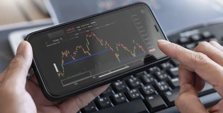 A team of business people collaborates in a meeting room, analyzing graphs on a large screen for an AI trading platform.